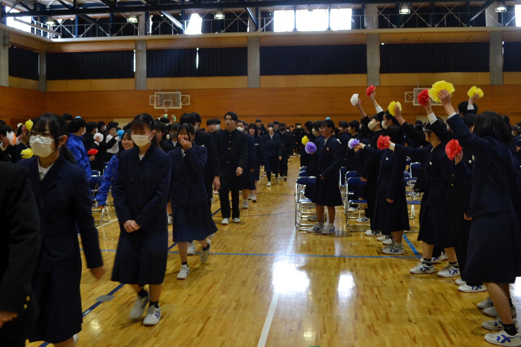 02 在校生は曲に合わせて紙花を振りながら３年生を迎えました